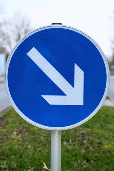 The traffic sign mandatory passing, right past, shows the lane to drive to. Street sign for the orientation of road users. Close up of a road sign.