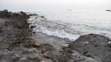 İtalya, Calabria 'daki Capo Vaticano' da Grotticelle sahilinde kayalar. Dalgalar kayaların üzerine akar. Tekne ve şamandıra arka planda görülebilir. Rahatlamış atmosfer.