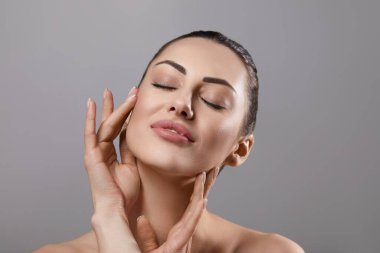 Temiz ciltli güzel bir genç kadın. Doğal çıplak makyajlı ve yüzüne dokunan güzellik modeli portresi. Spa, cilt bakımı ve sağlık. Yakın çekim, kopyalanma alanı.