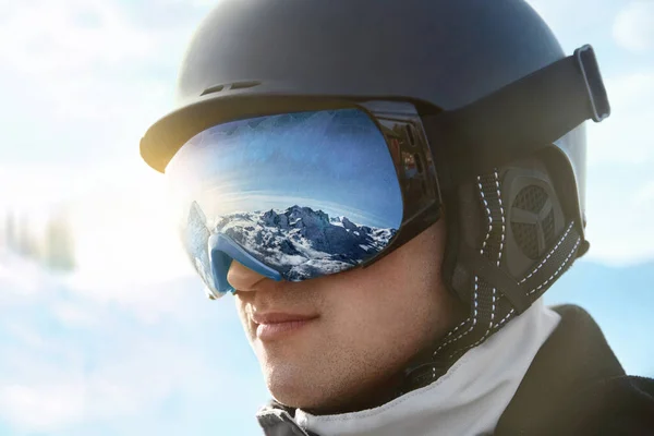 背景の青い空に男の肖像画は 雪の山の反射とスキーゴーグルを保持しています — ストック写真