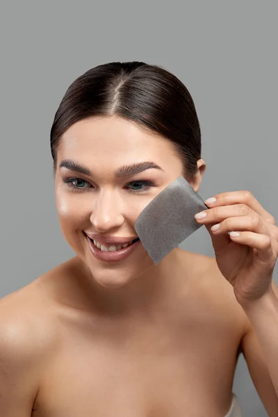 Beautiful woman using facial oil blotting paper.  Beauty concept. Cosmetology, cosmetics. Facial treatment