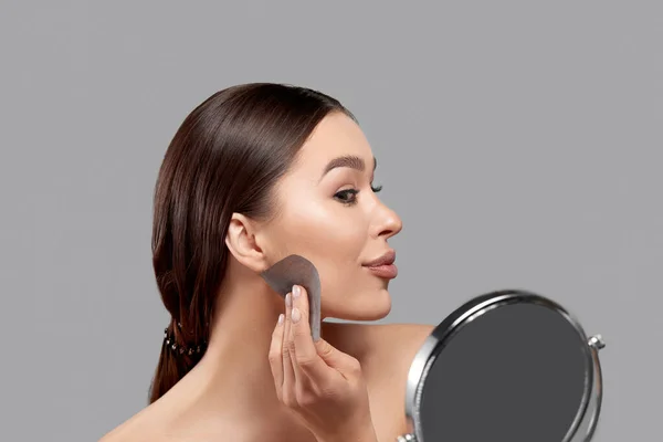 Beautiful woman using facial oil blotting paper.  Beauty concept. Cosmetology, cosmetics. Facial treatment