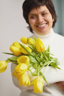 Portrait of positive charming cheerful old woman granny receive bunch of tulips smell close eyes enjoy 8-march celebration 