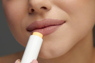 Yumuşak derili, dudak koruyucu ruj sürmüş bir kadının yakın çekimi. Dudaklar Deri Bakımı. Seksi Dolgun Dudaklı Güzel Kadın Yüzü Hijyenik Dudak Merhemi.