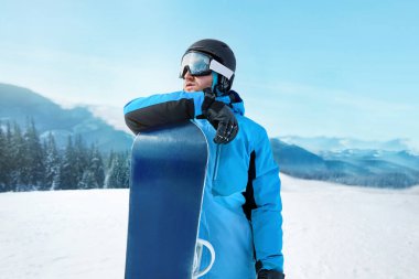 Kayak merkezindeki snowboardcu. Arka plandaki mavi gökyüzünde. Snowboard yapma. Kayak gözlüğü takıyor. Kar Dağlarının Yansımasıyla Kayak Gözlükleri
