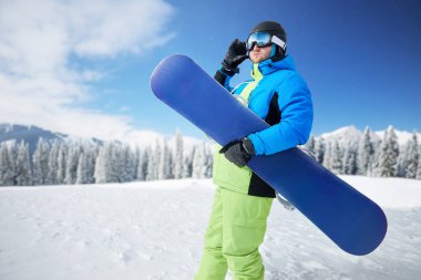 Arka plandaki kayak merkezinde kayak yapan adamın portresi snowboard yapıyor. Kayak gözlüğü takıyor.