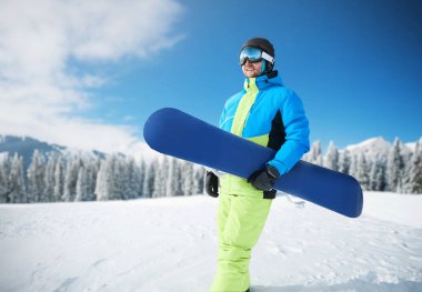 Kayak merkezindeki snowboardcu. Arka plandaki mavi gökyüzünde. Snowboard yapma. Kayak gözlüğü takıyor. Kar Dağlarının Yansımasıyla Kayak Gözlükleri