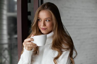 Kafede kahve içen genç bir kadının portresi.