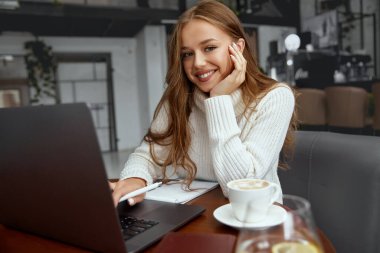 Masada oturan ve elinde cep telefonu olan güzel bir kadın.