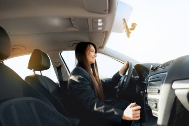 Güzel taksi şoförü, otomobil blogcusu ve araba yolcusu. Gülümseyen kadın direksiyonu tutuyor, hızını değiştiriyor..