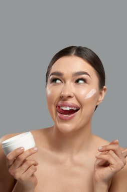 Skin care. Beauty Concept. Young woman holding cosmetic moisturizing cream. Portrait of girl face with clean healthy skin. Dermatology