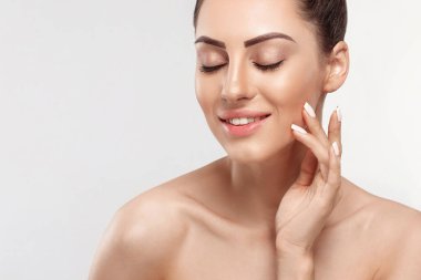 Temiz ciltli güzel bir genç kadın. Doğal çıplak makyajlı ve yüzüne dokunan güzellik modeli portresi. Spa, cilt bakımı ve sağlık. Kopyalama alanı.