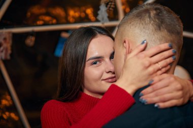 Genç aşık çift siyah arka planda birbirlerine sarılıyorlar.