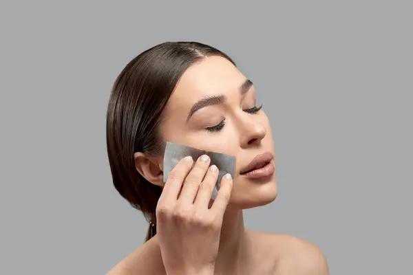 Hermosa Mujer Atractiva Usando Película Limpia Aceite Facial Para Eliminar Fotos de stock