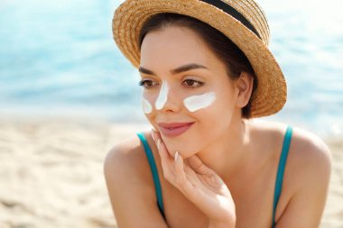 Güzel kadın tabaklanmış bir yüze krem güneş kremi uyguluyor. Güneş. Cilt ve vücut bakımı. Kız cildi için güneş kremi kullanıyor. Güneş losyonu tutan ve nemlendirici güneş kremi tutan bir kadın portresi.