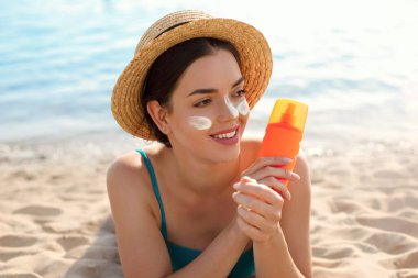 Güzel kadın tabaklanmış yüzüne krem güneş kremi uygulayarak. Güneş. Cilt ve vücut bakımı. Kız cildi için güneş kremi kullanıyor. Güneş losyonu tutan ve nemlendirici güneş kremi tutan bir kadın portresi.