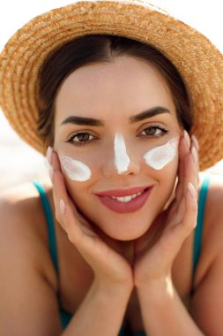 Güzel kadın tabaklanmış bir yüze krem güneş kremi uyguluyor. Güneş. Cilt ve vücut bakımı. Kız cildi için güneş kremi kullanıyor. Güneş losyonu tutan ve nemlendirici güneş kremi tutan bir kadın portresi.