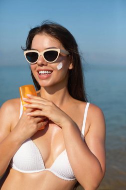 Güzel kadın tabaklanmış bir yüze krem güneş kremi uyguluyor. Güneş. Cilt ve vücut bakımı. Kız cildi için güneş kremi kullanıyor. Güneş losyonu tutan ve nemlendirici güneş kremi tutan bir kadın portresi.