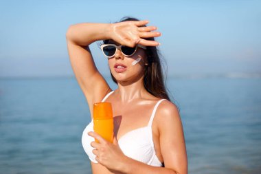 Güzel kadın tabaklanmış bir yüze krem güneş kremi uyguluyor. Güneş. Cilt ve vücut bakımı. Kız cildi için güneş kremi kullanıyor. Güneş losyonu tutan ve nemlendirici güneş kremi tutan bir kadın portresi.