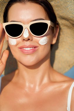 Kadın uygulanan güneş kremi yüzündeki gülümseme. Cilt Bakımı. Vücut güneş koruması. Güneş kremi. Kadın şapka smear losyon cildinize nemlendirici.