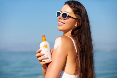 Beauty Woman bronzlaşmış omzuna güneş kremi sürüyor. Cilt bakımı. Vücut Güneş koruması 