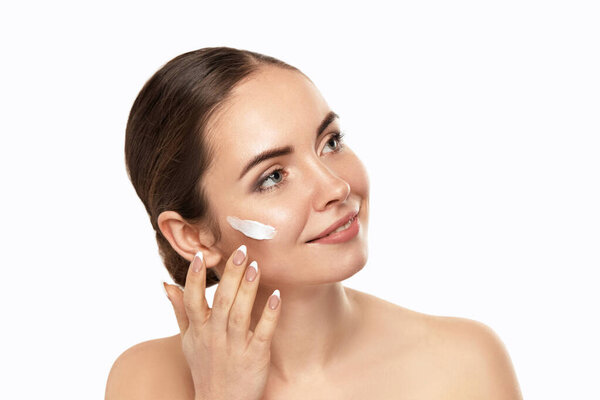 Косметика кожи. Портрет красивой молодой девушки, наносящей тональный крем на лицо. Крупный план улыбающейся женщины с чистой здоровой кожей и идеальным профессиональным макияжем. Красота лица
. 