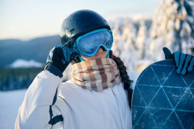 Snowboard tutan ve kayak gözlüğü takan bir kadının portresi. Kar Dağlarının Yansıması ile Snowboardcunun Kayak Gözlükleri.