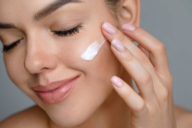 Cilt bakımı. Güzel yüzlü kadın sağlıklı yüz portresine dokunuyor. Güzel bir kız model krem sürmeye başladı.