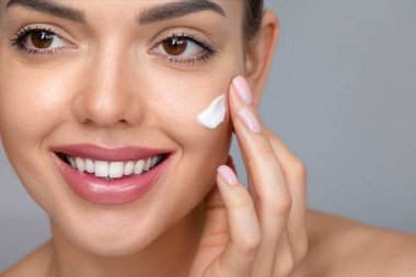 Temiz ciltli güzel bir genç kadın. Doğal çıplak makyajlı ve yüzüne dokunan güzellik modeli portresi. Spa, cilt bakımı ve sağlık. Yakın çekim, kopyalanma alanı.