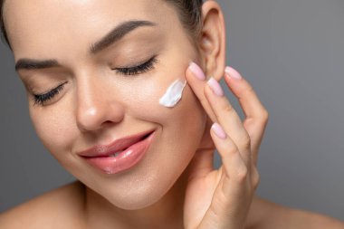 Temiz ciltli güzel bir genç kadın. Doğal çıplak makyajlı ve yüzüne dokunan güzellik modeli portresi. Spa, cilt bakımı ve sağlık. Yakın çekim, kopyalanma alanı.