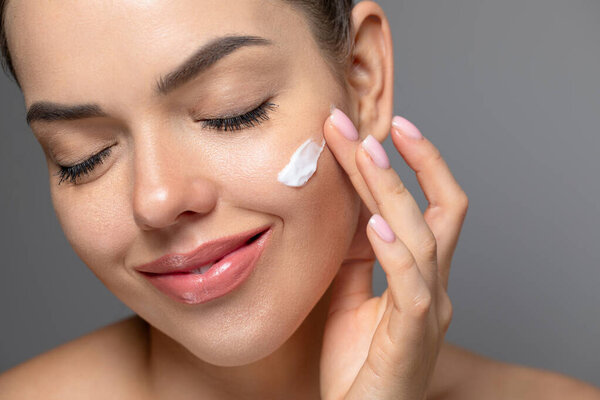 Красивая молодая женщина с чистой идеальной кожей. Портрет модели красоты с натуральным обнаженным макияжем и прикосновением к лицу. Spa, skincare и wellness. Close up, copyspace.