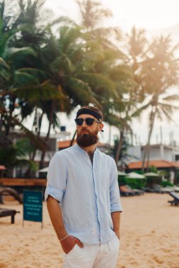 Kumsalda tişörtlü yakışıklı sakallı adamın portresi.