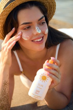 Güzel kadın yüzüne güneş kremi sür. Plajda güneş kremi sürmüş bir kadın. Kadın Tutucu Nemlendirici Güneş kreminin Portresi. Güneş kremi kullanan bir kız. Cilt Bakımı Konsepti. Güneş koruması. 