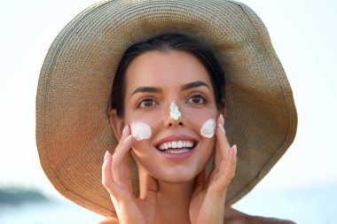 Güzellik, güneş kremi ve cilt bakım ürünleri yüz portresi nemlendirici kremi olan kadın. Derisi için güneş kremi kullanan bir kız. Güneş kremi ya da yanağında güneş kremi..