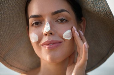 Güzel Kadın Yüze Nemlendirici Uygula. Güneş kremi kullanan bir kız. Kadın Smears 'ın Portresi. Cilt Bakımı Konsepti. Güneş koruması. Güneş losyonu 