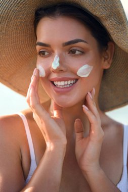 Güzel Kadın Yüze Nemlendirici Uygula. Güneş kremi kullanan bir kız. Kadın Smears 'ın Portresi. Cilt Bakımı Konsepti. Güneş koruması. Güneş losyonu.