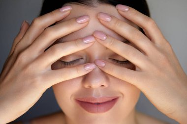 Uzun siyah saçlı bir kadının, alnına nazikçe parmakları ve gözleri kapalı masaj yapması ve stresten kurtulurken sakin bir anın tadını çıkarması gibi, rahatlama da sahnenin ortasına yerleşir..