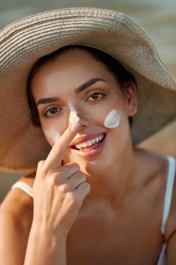 Güzel kadın tabaklanmış bir yüze krem güneş kremi uyguluyor. Güneş. Cilt ve vücut bakımı. Kız cildi için güneş kremi kullanıyor. Güneş losyonu tutan ve nemlendirici güneş kremi tutan bir kadın portresi.