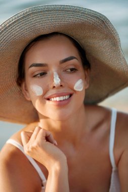 Kadın uygulanan güneş kremi yüzündeki gülümseme. Cilt Bakımı. Vücut güneş koruması. Güneş kremi. Kadın şapka smear losyon cildinize nemlendirici.