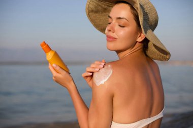 Bikini Güzel Kadın Tabaklanmış Omuz Güneş Kremi Uygulayarak. Güneş koruma. Cilt ve Vücut Bakımı. Cilt için Güneş Kremi Kullanarak Kız. Kadın Holding Suntan Losyonu ve Nemlendirici Güneş Kremi Portresi.