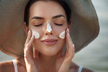 Güzellik, güneş kremi ve cilt bakım ürünleri yüz portresi nemlendirici kremi olan kadın. Derisi için güneş kremi kullanan bir kız. Güneş kremi ya da yanağında güneş kremi.