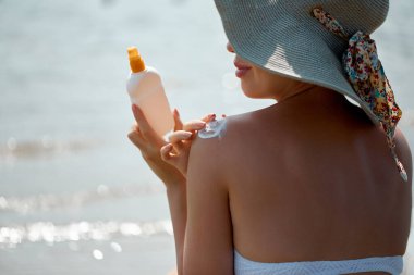 Bir kadın uygulamak güneş kremi Creme tabaklanmış omuz. Güneşten korunma. Güneş koruması, güvenli güneş kremi cildi sağlıklı kullanan kız.