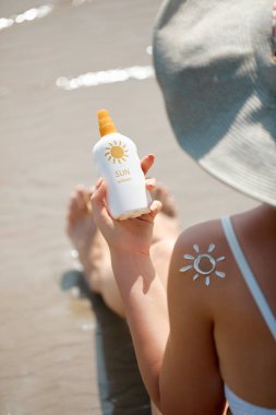 Güzel kadın bronzlaşmış bacaklarına güneş kremi sür. Cilt bakımı. Kadın elinin nemlendirici losyon sürmesine yakın çekim. Güneş kremi kavramı.