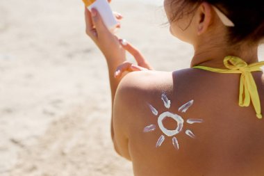 Bronzlaşmış omuzda güneş kremi. Güneş koruması. Güneş kremi süren bikinili güzel bir kadın. Deri ve vücut bakımı. Güneş kremi ya da nemlendirici güneş kremi tutan kadın portresi.