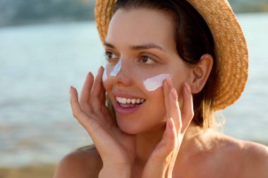 Güneş kremi güneş kremi uygulayan güneş losyonu kadın. Güzel mutlu sevimli kadın burnuna güneş kremi uygulayarak.