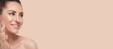 Close-up portrait of a woman with radiant, glowing skin gently touching her face. Her flawless complexion and smooth skin make this image perfect for beauty, makeup, and skincare promotion