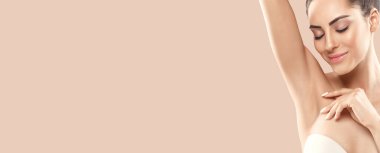 Armpit epilation, lacer hair removal. Young woman holding her arms up and showing clean underarms, depilation  smooth clear skin .Panorama baner With Copy Space