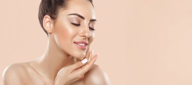 Beautiful smiling woman with healthy smooth facial clean skin applying cosmetic cream and touch own face. Model with  Beauty face. Skin care Moisturizer Facial treatment. Panorama baner With Copy Space