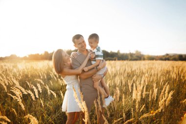 Bir aile sıcak bir öğleden sonra altın buğday tarlasında gülüp kucaklaşır. Güneş, doğadaki neşe ve birlikteliklerini vurgulayan yumuşak bir parıltı saçar..