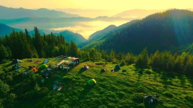 Sunrise 'da Çadırlarla Manzaralı Dağ Kampı. Gün doğumunda dağlarda yuva yapmış bir kamp alanının nefes kesici manzarası.